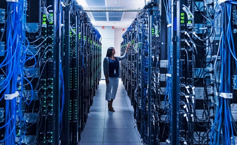 woman standing in between a bunch of server racks