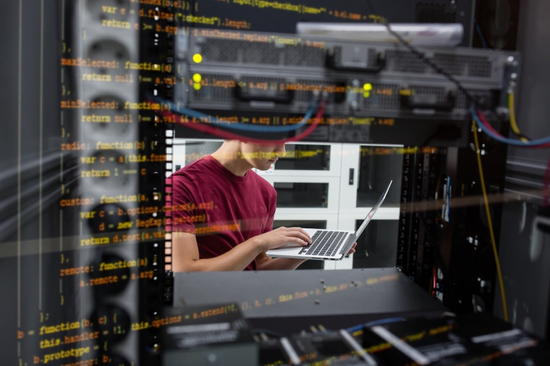 Close up of an unrecognizable young businessman holding a laptop in a server room