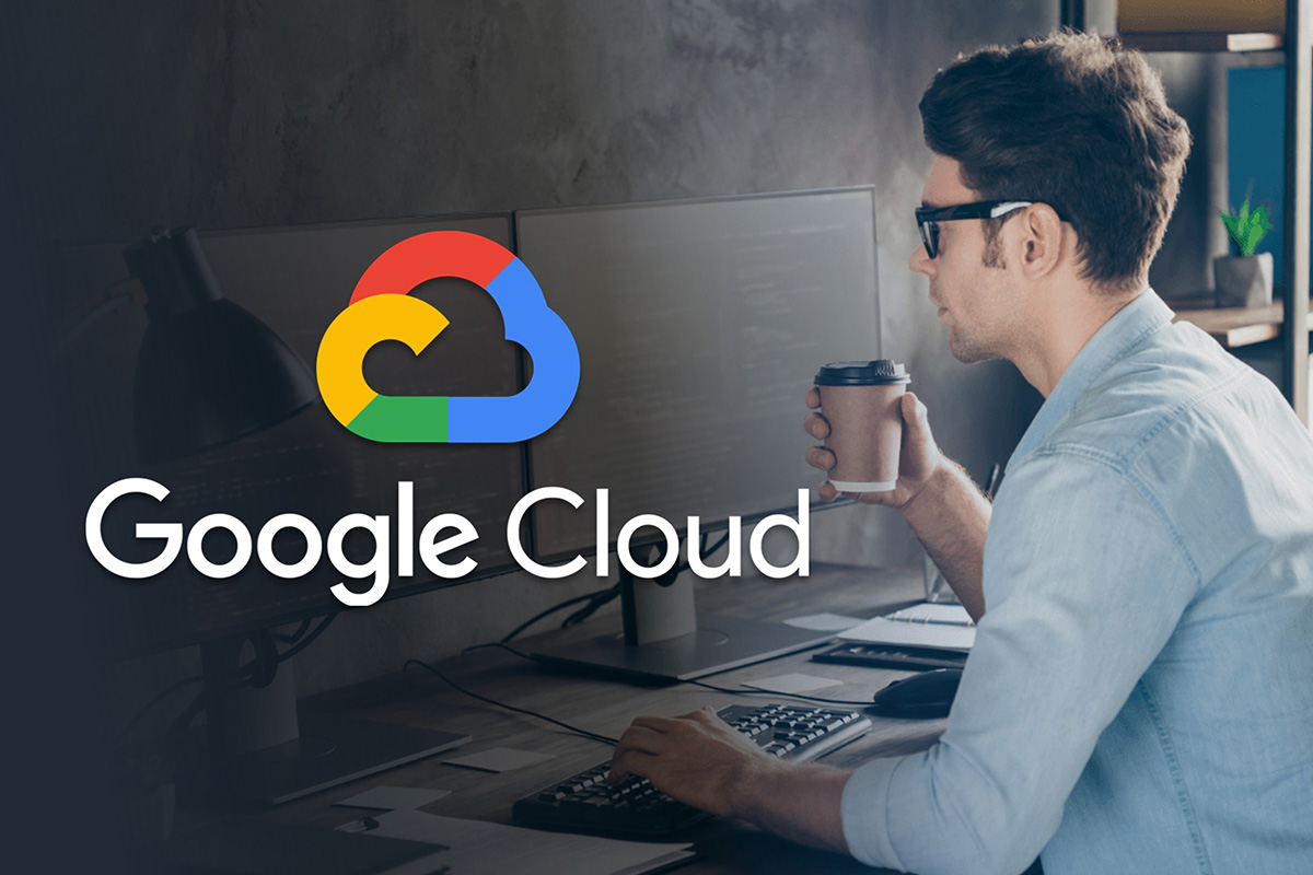 Google Cloud logo hovering over a man working at a computer while drinking from a hot beverage